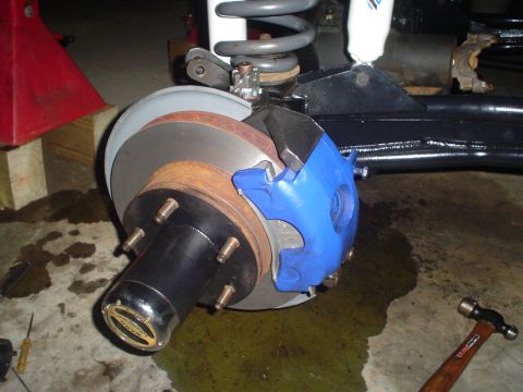 1984 Ford Bronco - Close-up of a vehicle's front wheel brake assembly, showing the rotor and blue caliper.