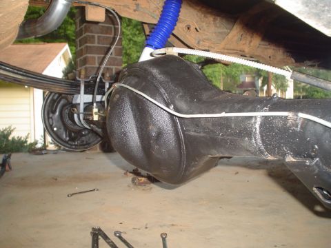 1984 Ford Bronco - The underside of a vehicle shows the rear axle assembly and suspension components, including leaf springs and a shock absorber.