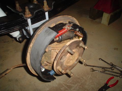 1984 Ford Bronco - Close-up of a vehicle's brake drum assembly, showing internal components and surrounding tools.