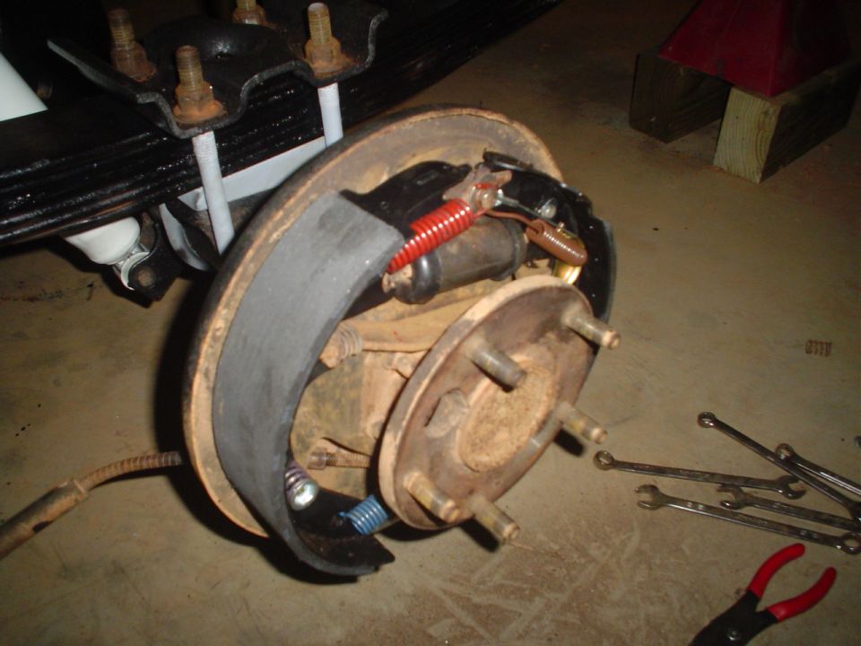 Disassembled rear drum brake showing shoes, wheel cylinder and springs on the axle flange