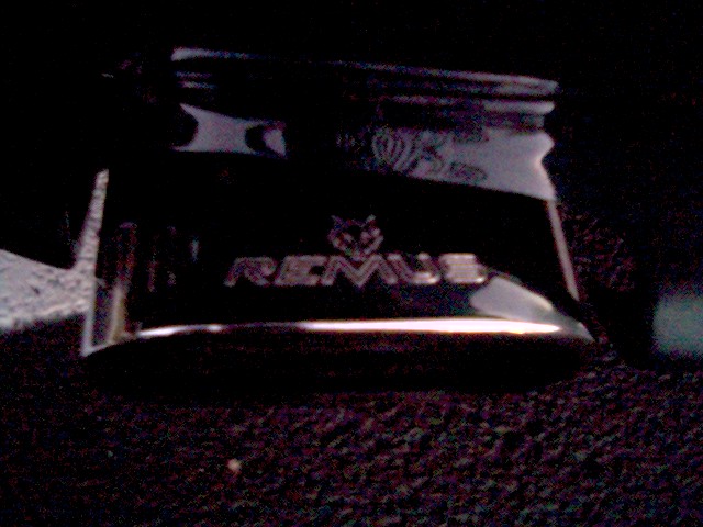 Chrome Remus exhaust tip with engraved logo, photographed at night