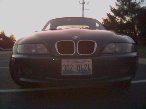 1996 BMW Z3 - The front grille and headlights of a dark-colored BMW Z3 are visible under a bright sky.