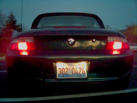 1996 BMW Z3 - The rear of a 1996 BMW Z3 is shown at dusk, with its taillights and license plate illuminated.