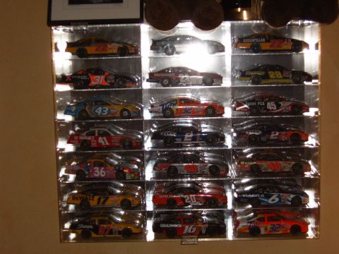 1993 Ford Bronco - A collection of miniature race cars are neatly displayed in a lighted case on a shelf.