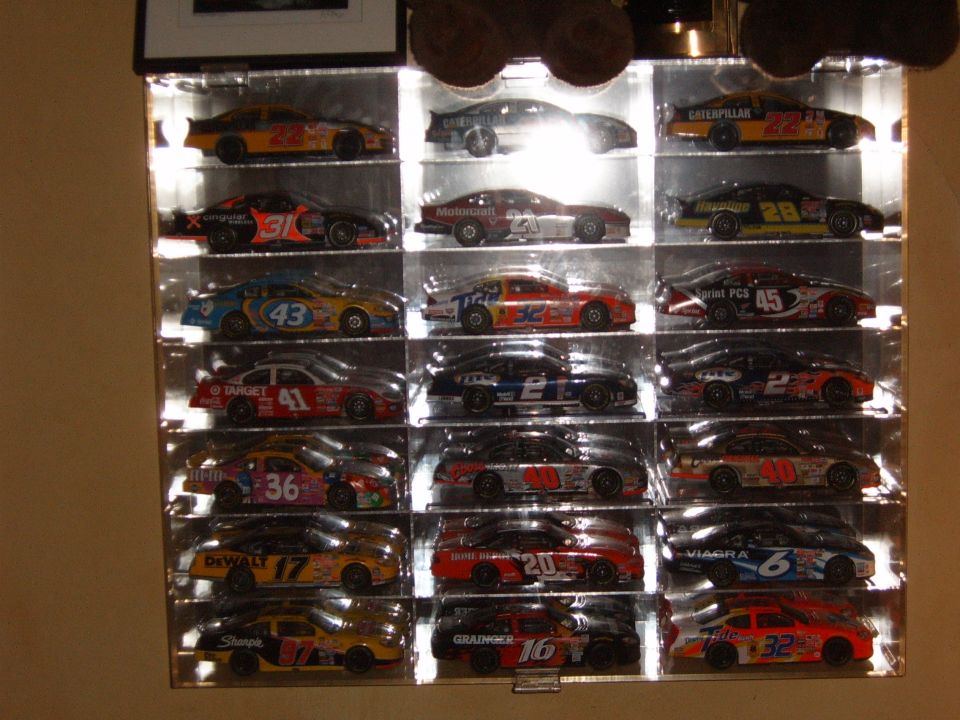 Display case with 15 NASCAR diecast cars, each with sponsor logos and numbers