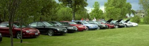 1997 Ford Taurus - A row of 1997 Ford Tauruses are parked on a grassy field during a meeting.