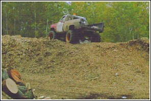 1976 Chevrolet Silverado 2500 - A heavily modified pickup truck navigates a steep dirt incline, its build suited for off-road challenges.