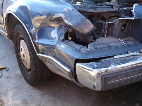 1989 Lincoln Continental - Front end damage on a 1989 Lincoln Continental, showing a missing headlight and bent fender.