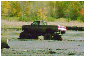 1976 Chevrolet Silverado 2500 - Pickup truck with large tires stuck in mud during a mud run event.