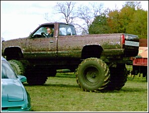 1976 Chevrolet Silverado 2500 - This heavily modified pickup truck is covered in mud, suggesting it has been used for off-road activities.