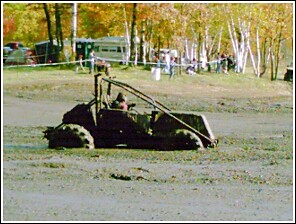 1976 Chevrolet Silverado 2500 - An off-road buggy is seen stuck in the mud during a mud run event, with spectators in the background.