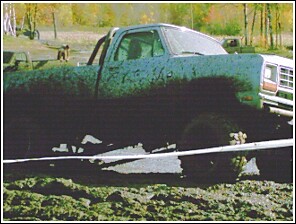 1976 Chevrolet Silverado 2500 - A heavily mud-covered truck is seen in a muddy environment, with another vehicle visible behind it.