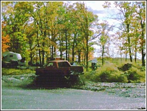 1976 Chevrolet Silverado 2500 - A truck is stuck in a muddy area, with trees and other vehicles in the background. The SuperMotors logo is visible in the lower right corne…