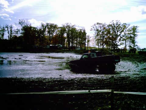 1976 Chevrolet Silverado 2500 - A black pickup truck navigates a muddy course during a mud run event.