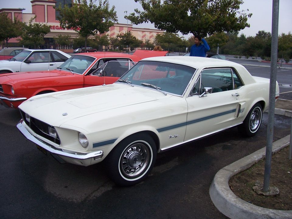 White 1967 Ford Mustang parked next to a red Mustang