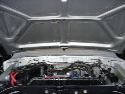 1979 Ford Bronco - The engine bay of a 1979 Ford Bronco is visible with the hood open, revealing the engine and various components.
