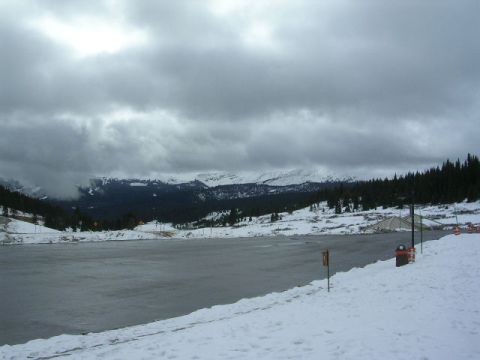 1975 Ford Ranchero - A vast, snow-covered landscape unfolds with a frozen lake in the foreground and mountains in the distance under a dramatic sky.
