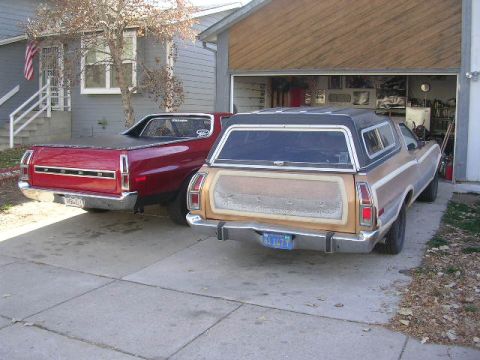 1975 Ford Ranchero - Two Ford Rancheros, a red one and a tan one with a camper shell, are parked in a driveway next to a garage.