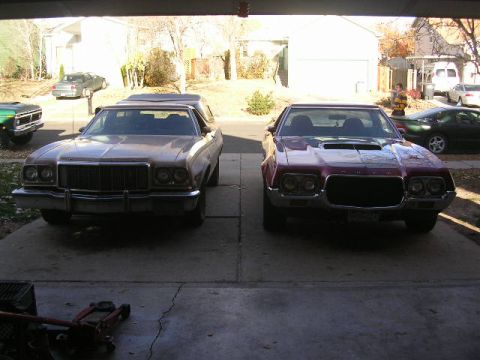 1975 Ford Ranchero - Two Ford Rancheros are parked side-by-side in a driveway, with one showing a prominent grille and the other a hood scoop.