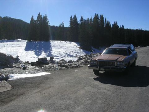 1975 Ford Ranchero - A 1975 Ford Ranchero with a camper shell is parked in a snowy landscape under a clear blue sky.