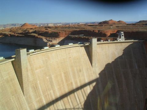 1975 Ford Ranchero - A large concrete dam stretches across a body of water, with arid hills in the background under a clear blue sky.