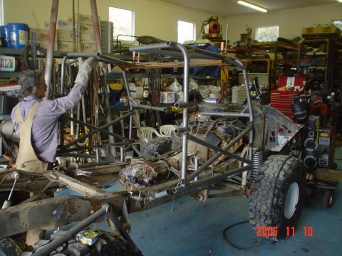 1978 Ford Bronco - A person is welding a roll cage onto a custom off-road vehicle chassis in a workshop.