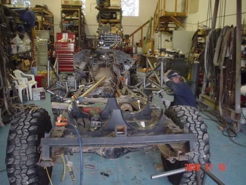 1978 Ford Bronco - A vehicle chassis is under construction in a workshop, with a person welding in the background.