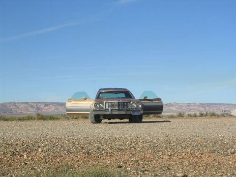1975 Ford Ranchero - A 1975 Ford Ranchero sits on a gravel lot, its doors open to the desert scenery under a clear blue sky.