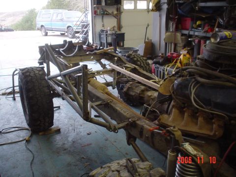 1978 Ford Bronco - A custom off-road chassis is shown in a garage, with a blue pickup truck visible in the background.