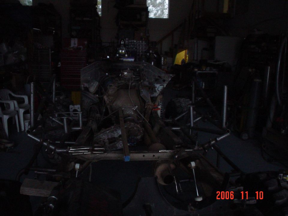 Vehicle frame with engine parts and suspension components in a workshop. Date stamp reads 2006 11 10