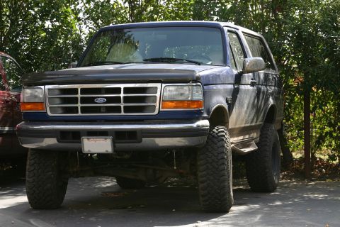 1996 Ford Bronco - This lifted Ford Bronco is parked outside with trees in the background.