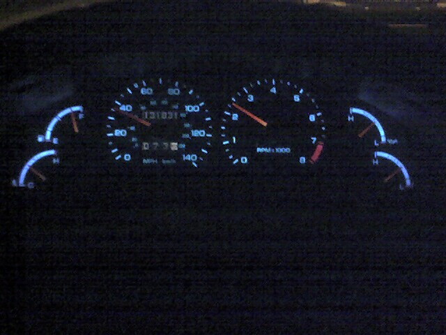 Car dashboard with illuminated speedometer, tachometer, and fuel/temp gauges