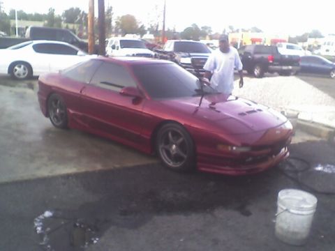 1994 Ford Probe - A red coupe is being washed in a parking lot with other vehicles in the background.