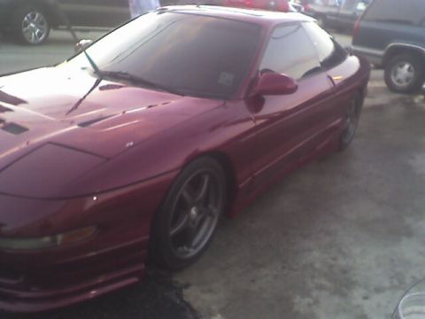 1994 Ford Probe - A maroon coupe is parked on a concrete surface with other vehicles visible in the background.