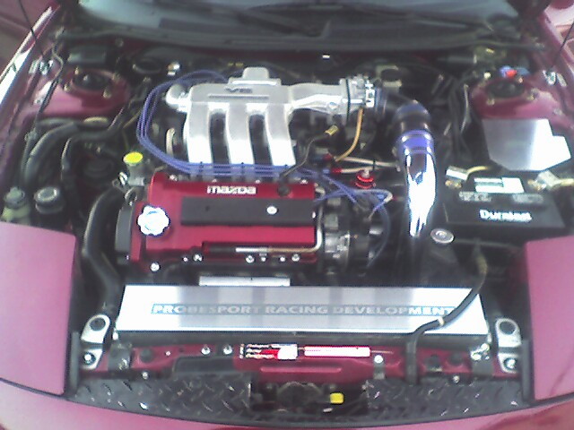 Engine bay with a red Mazda engine, silver intake manifold, and a "PROBESPORT RACING DEVELOPMENT" plate