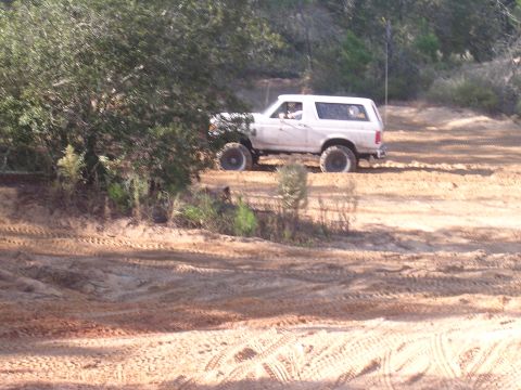 2006 Ford F-150 - A white Ford Bronco navigates a sandy off-road path, kicking up dust.