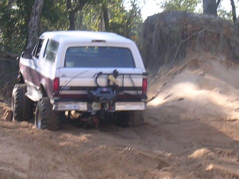 2006 Ford F-150 - A lifted Ford Bronco navigates a sandy trail, its rear end visible as it climbs.