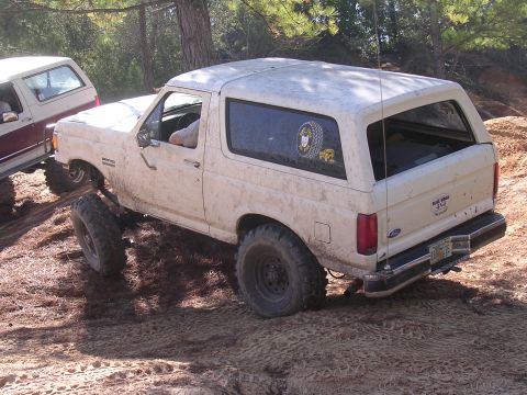 2006 Ford F-150 - A white Ford Bronco navigates a muddy off-road trail with another vehicle visible behind it.