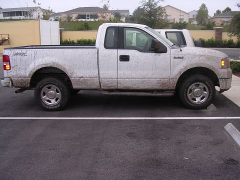 2006 Ford F-150 - Mud-covered 2006 Ford F-150 pickup truck parked after an off-road trip.