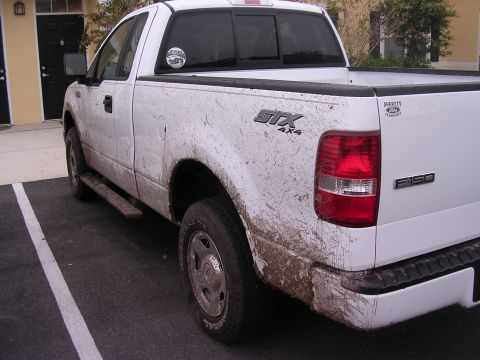 2006 Ford F-150 - This white Ford F-150 pickup truck is heavily covered in mud after an off-road excursion.