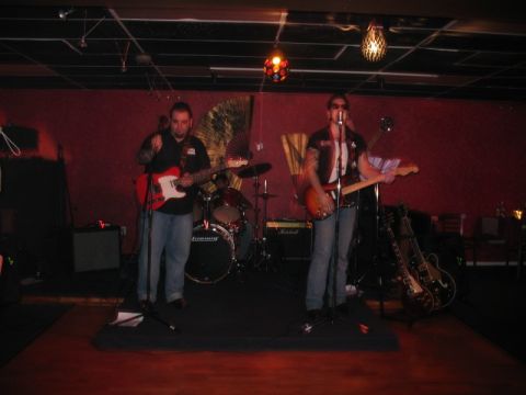 1997 Ford Crown Victoria - A band plays a gig on a stage with red walls and decorative lighting.