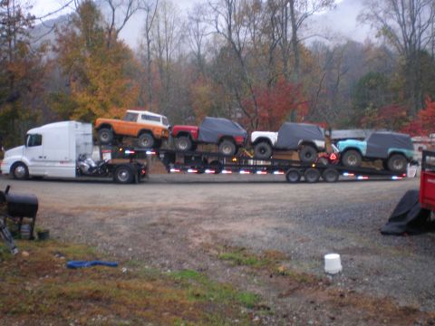 1969 Ford Bronco - A fleet of SUVs, including an orange 1969 Ford Bronco, are transported on a large trailer.