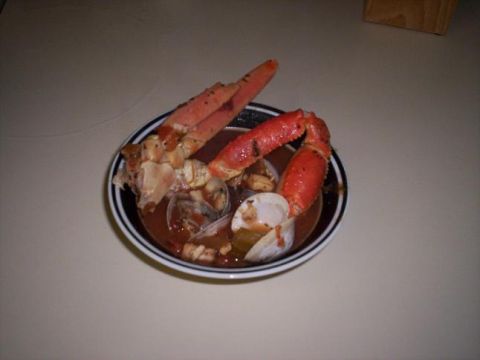 1989 Ford Bronco - A bowl of seafood stew or cioppino on a countertop, holding crab legs, clams and shrimp in a tomato broth. No vehicle content.