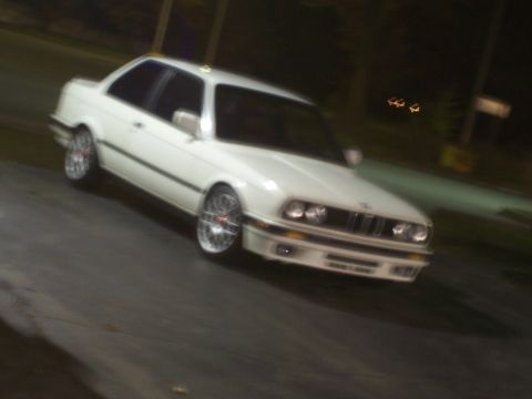 1992 Mercury Grand Marquis - A white BMW coupe is shown from a three-quarter front view at night.