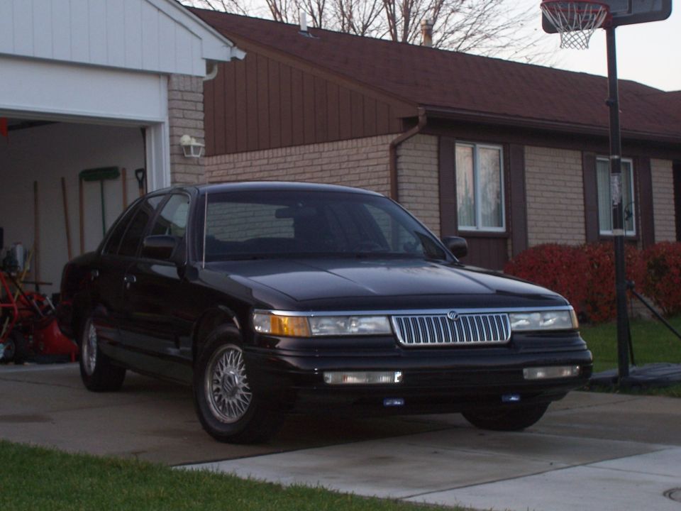 Black Mercury Grand Marquis sedan parked in a residential driveway