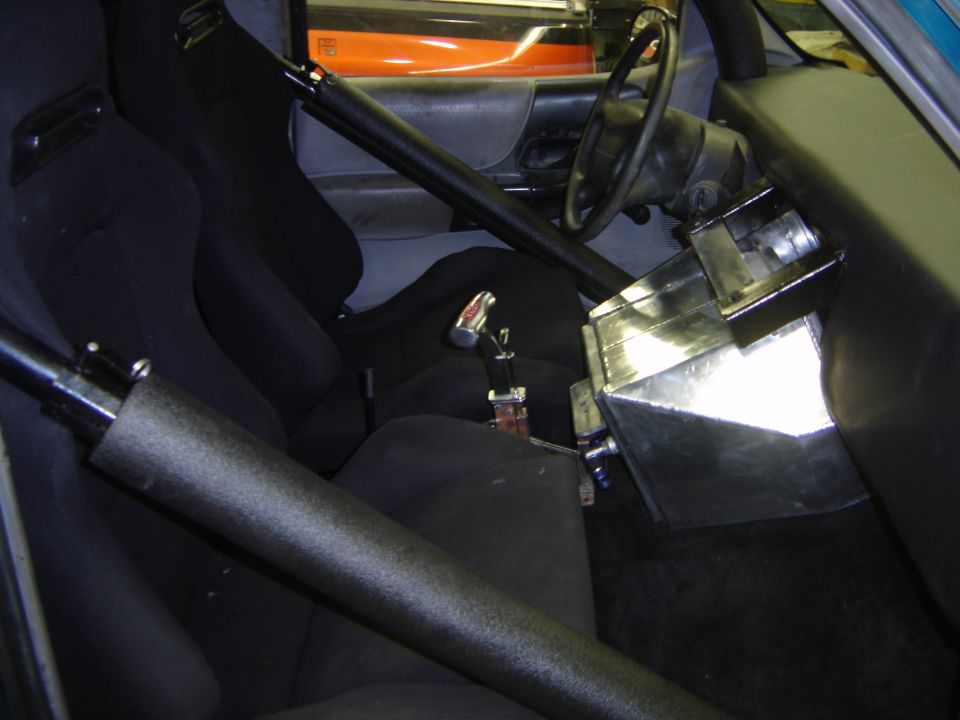 Gutted truck interior with roll cage, bucket seat, floor shifter and bare aluminum console