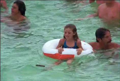1991 Ford Bronco - A young girl floats in a pool with an inflatable ring while adults swim around her.