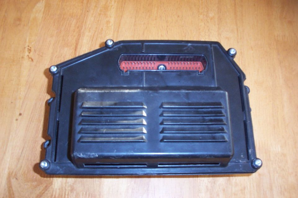 Black engine control module with red connector and ventilation slots