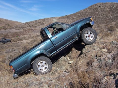1995 Toyota Hilux - Teal 1995 Toyota Hilux navigating a steep, rocky trail with another vehicle visible in the distance.