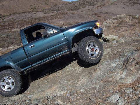1995 Toyota Hilux - Teal 1995 Toyota Hilux navigating a rocky trail with one wheel off the ground.